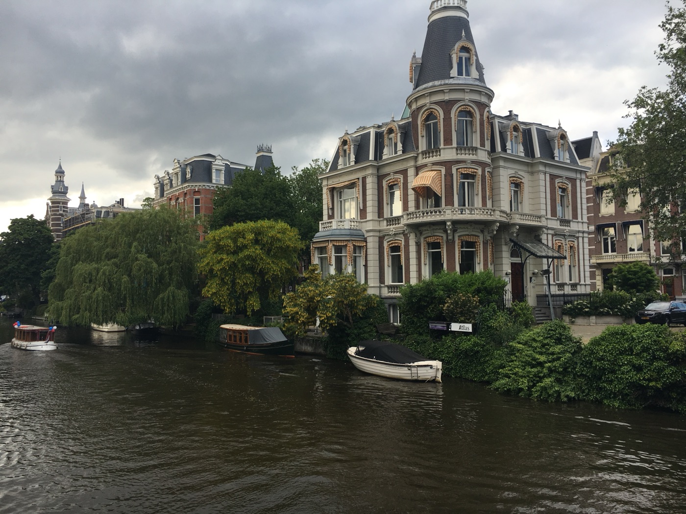An ornate Amsterdam house beside a canal under a cloudy sky