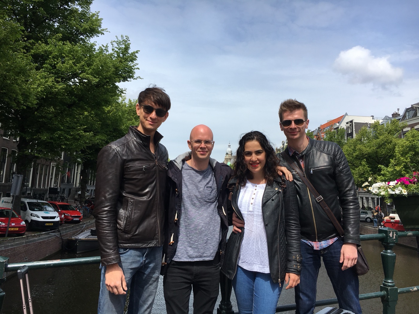 Four friends standing together on a bridge over an Amsterdam canal